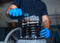 A man wearing blue latex gloves performs repair work on a air compressor pump