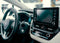 The cream and black interior of a car with the focus on the wheel, driver's area and especially the stereo system and central display.